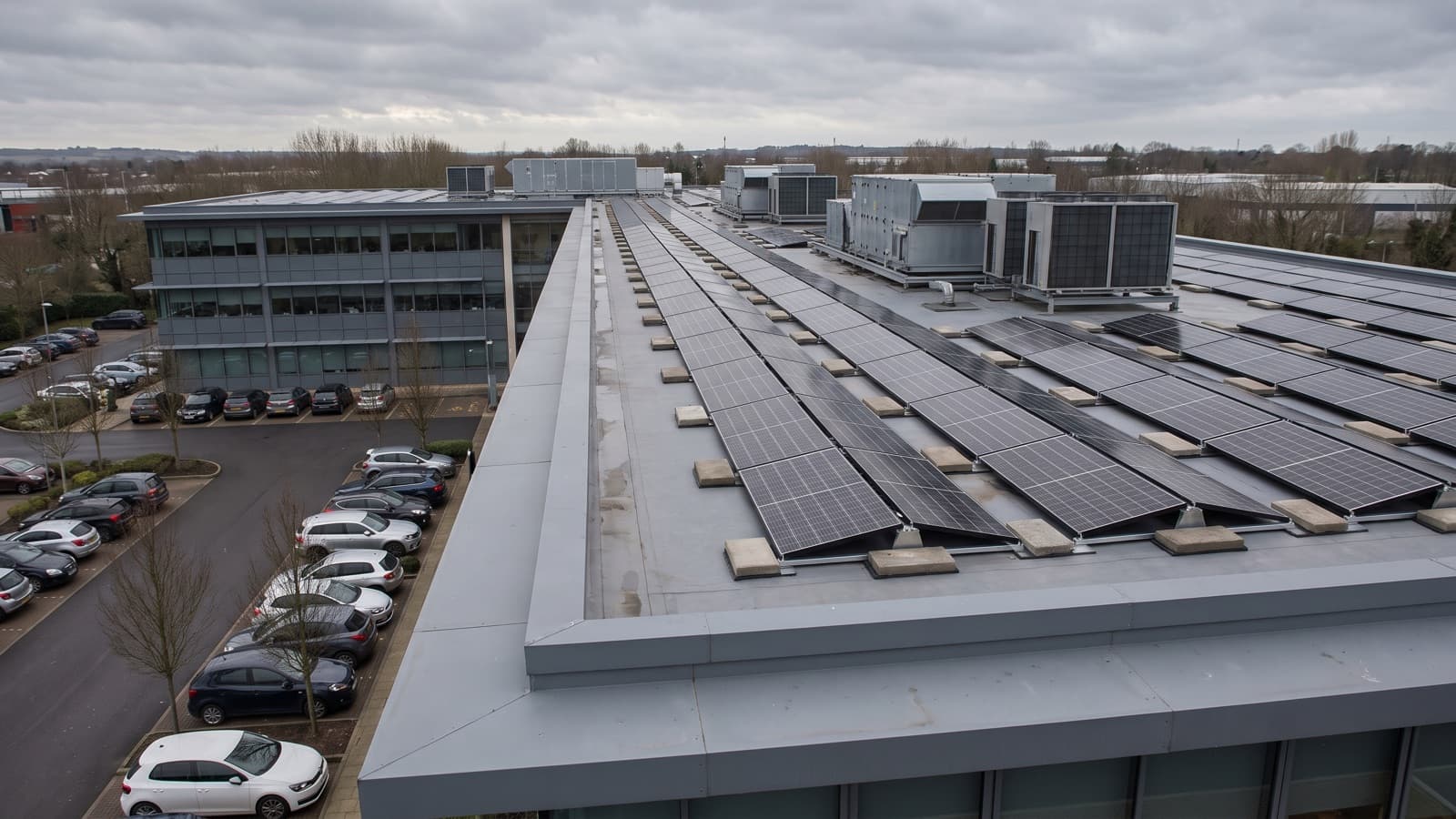 A business-park office block with a ballasted rooftop solar array laid out around its air-handling plant.